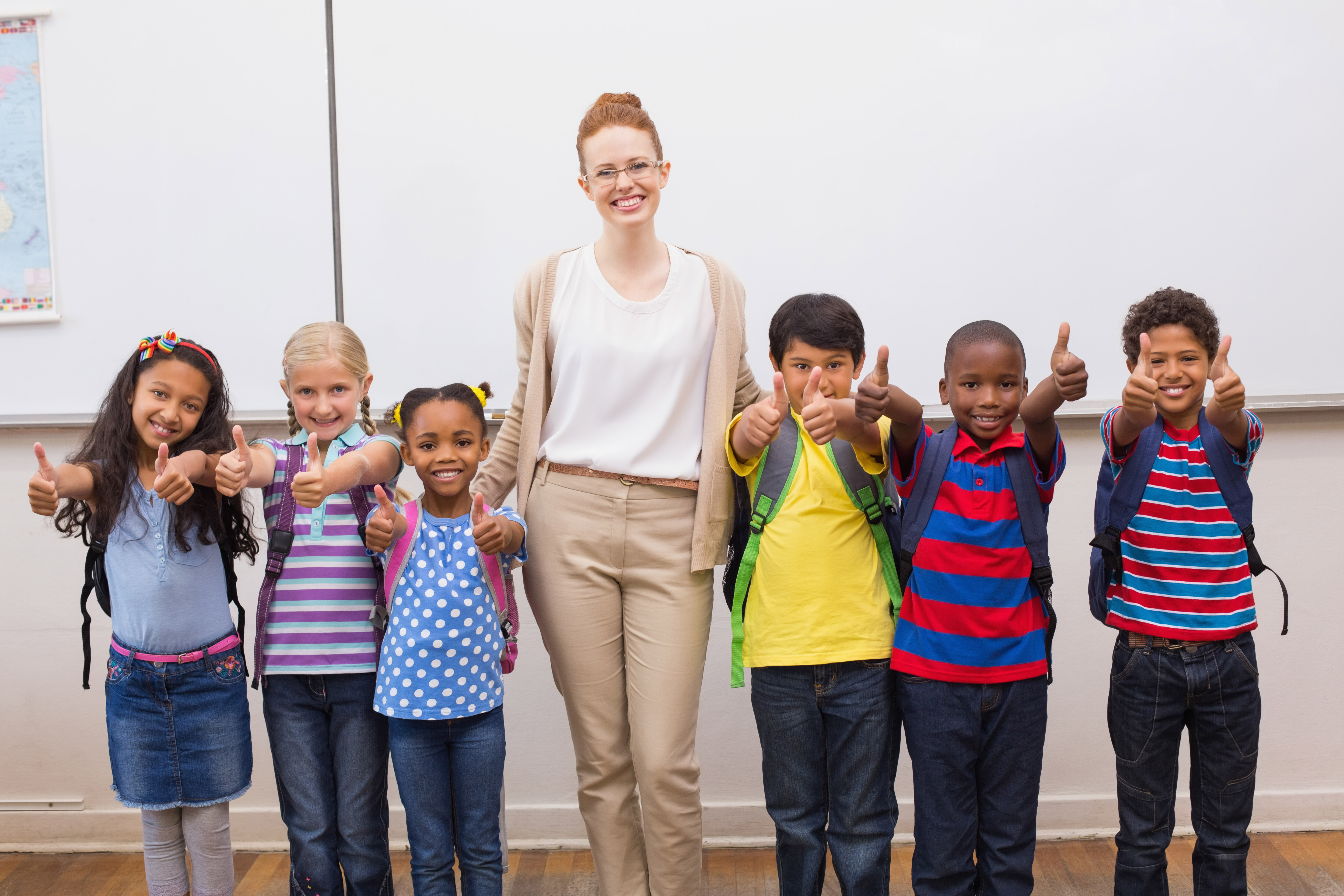 Teacher and pupils smiling at camera in classroom at the elementary school
